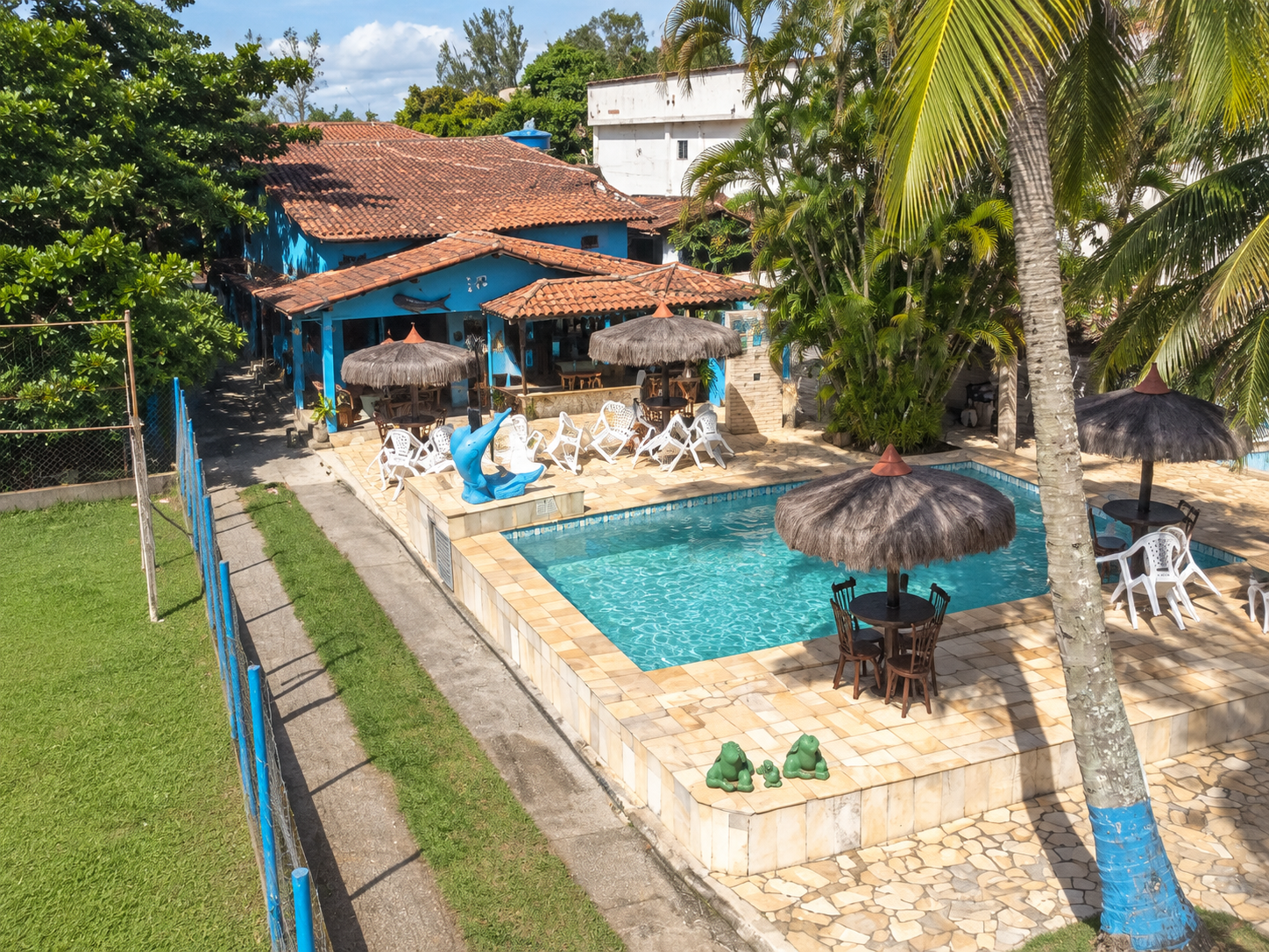 Piscina da pousada cercada de palmeiras e jardins